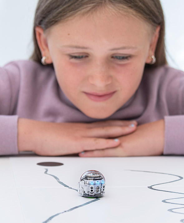 Schülerin beobachtet, wie Ozobot die Programmierung durchführt