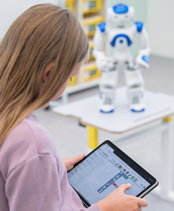 Kind programmiert am Tablet den NAO-Roboter