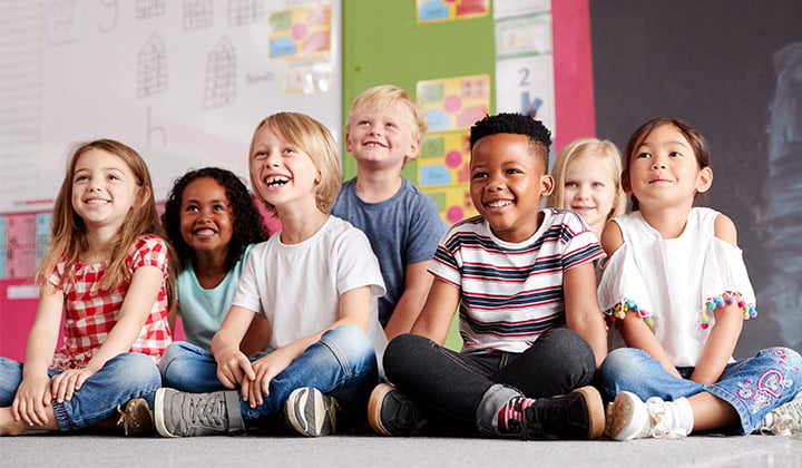 Kinder sitzen im Klassenzimmer auf dem Boden